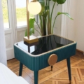 Stolik nocny Scappini Home Away, szary, z jedną szufladą, blat z lakierowanego szkła, wykończenie mosiężne, wyściełany ekoskórą.