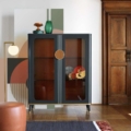 Scappini Home Smart Vitrine to szara, matowa witryna z mosiężnymi detalami, skórzanymi uchwytami, oświetleniem LED i półkami z dymnego szkła.